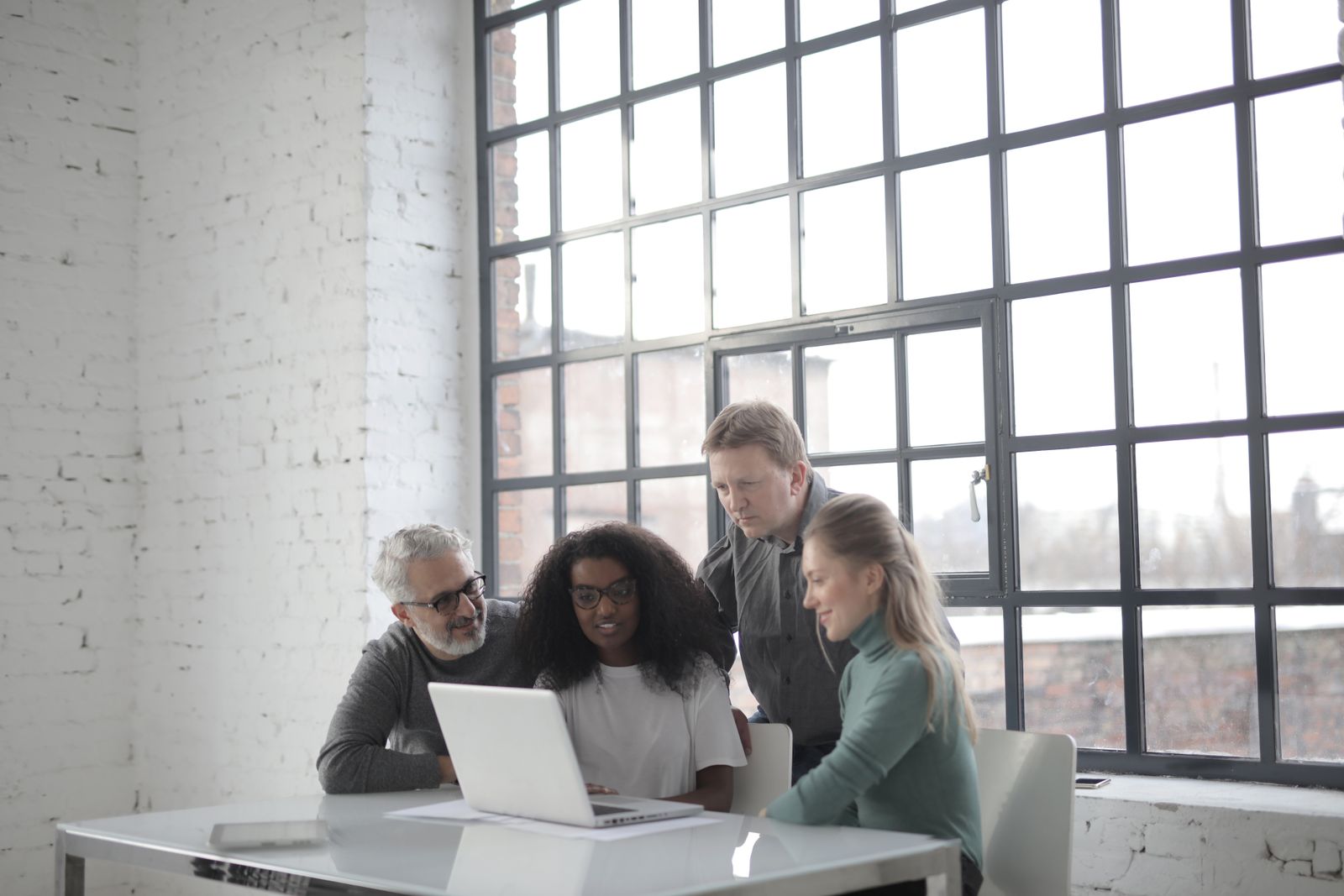 Four colleagues of different ages working together around a laptop