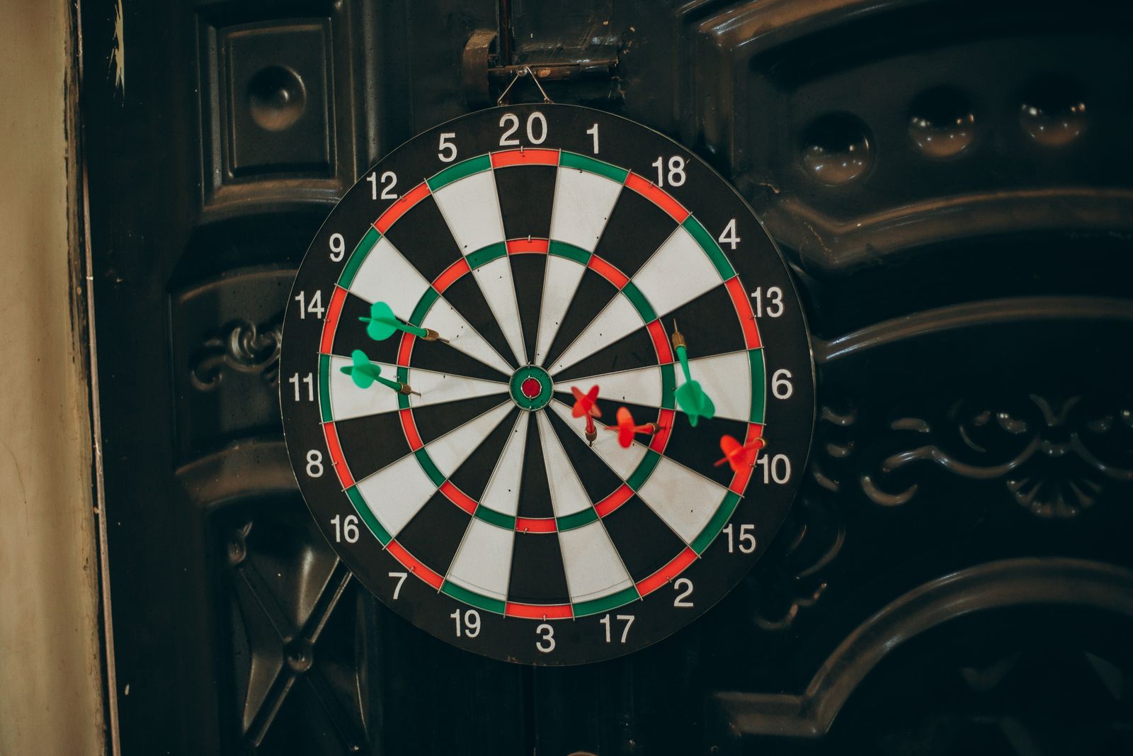 Darts scattered across a dartboard, most of them off the bullseye